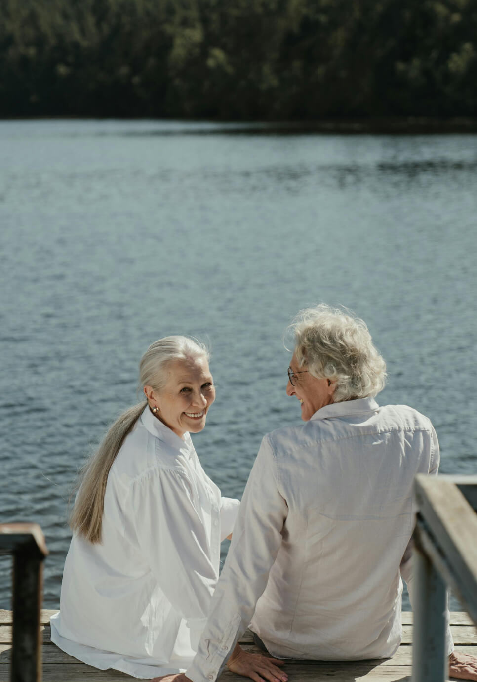 Pareja de ancianos sentados en un muelle de madera